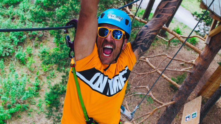 Kille på svensexa klättrar ett hinder med monkey bars på den röda banan, han skriker av förtjusning